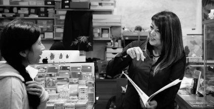 Black and white image of a woman holding an open book in a store