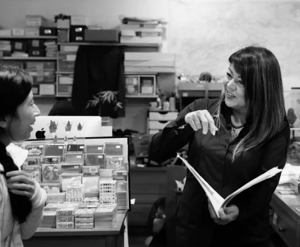 Black and white image of a woman holding an open book in a store