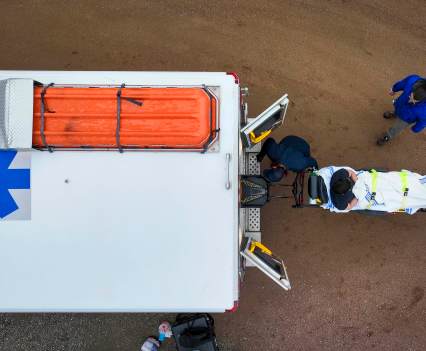 Aerial shot of the back of an ambulance being loaded with a stretcher