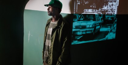 DonJuan Moses, next to a projection of police cars in Mission Hill after the Stuart shooting. DonJuan was 11 years old when police burst into his Mission Hill home and arrested his cousin.