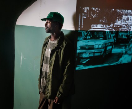 DonJuan Moses, next to a projection of police cars in Mission Hill after the Stuart shooting. DonJuan was 11 years old when police burst into his Mission Hill home and arrested his cousin.