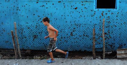 Cousin Oleksandr running in front of the Kolotylos’ shed that is full of damage from the war.