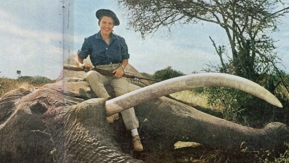 Virginia Kraft sits atop an African elephant, rifle in hand.