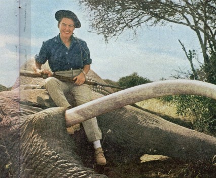 Virginia Kraft sits atop an African elephant, rifle in hand.