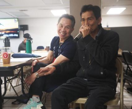 Photograph of a group of Vietnamese elders seated and singing karaoke