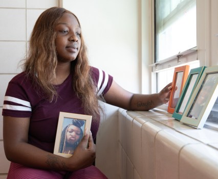 Photo of a Black woman looking at framed photographs and holding one in her hand