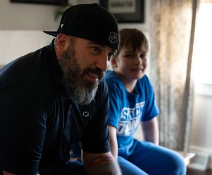 Photo of a man sitting in front of his son who has struggled with depression