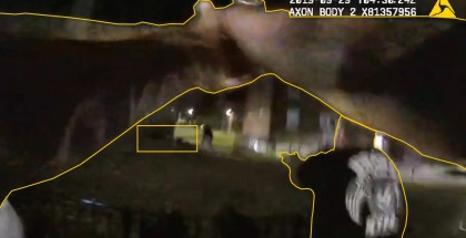 Still image from blurry body cam has yellow lines drawn on top of the blurry image to trace what appears to be hands holding a gun pointed at a person