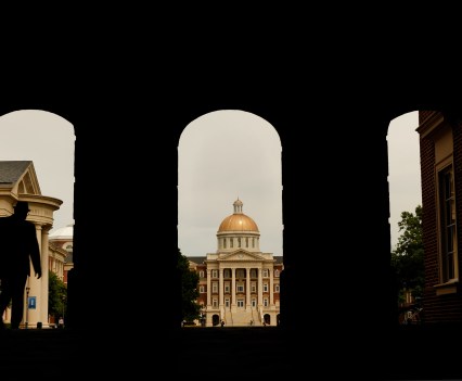 View from inside a shadowed archway shows a gold domed building with columns in the front