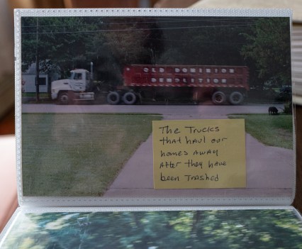 A photo of a large truck with a red trailer with white words on the side that say, "Old Dominion Demolition." There is a yellow sticky note on the photo that says, "The trucks that haul our homes away after they have been trashed"